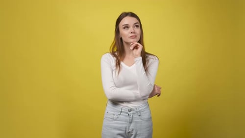 Young Woman Ponders in Front of Yellow Backdrop