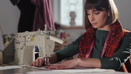 Young Girl In Sewing Studio Sews Behind Sewing Machine