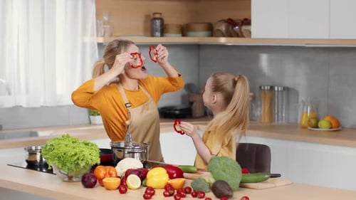 Mother and Daughter Playfully Cooking with Vegetables