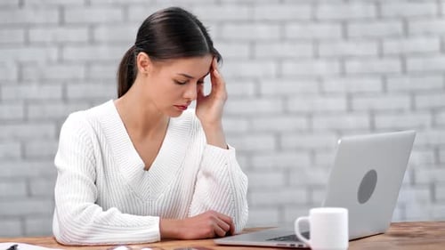 Woman with Headache Working on Laptop at Desk