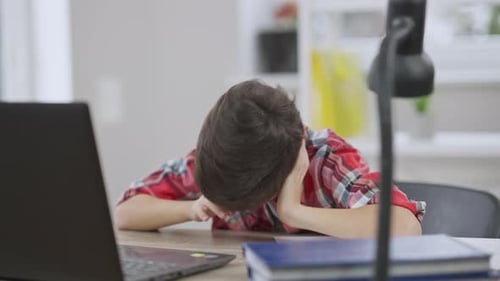 Tired Boy Resting Head at Desk with Laptop