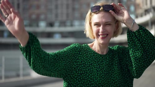 Woman Waving and Smiling in an Urban Setting