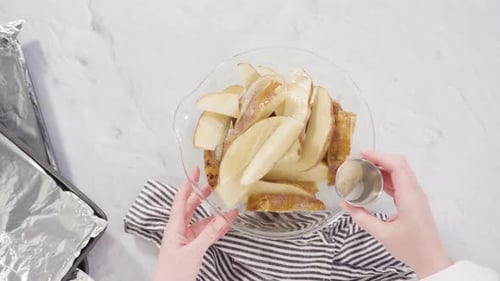Time lapse. Flat lay. Step by step. Preparing russet potatoes in wedges with olive oil and spices to