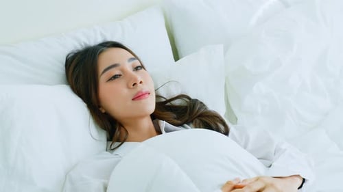 Woman Waking Up in Bed in Bright Bedroom