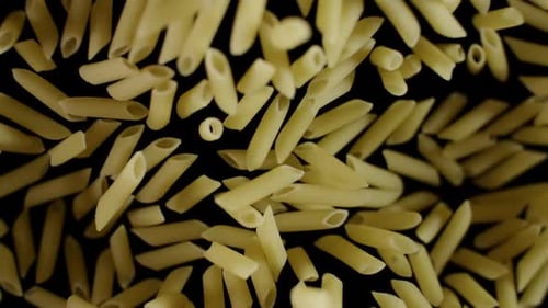 Penne Pasta Pieces Floating Against Black Background