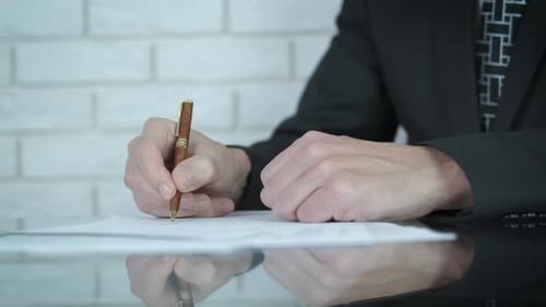 Man Signs a Contract at Desk with Fountain Pen