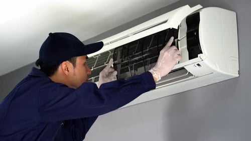 technician service placing back clean filter into air conditioner