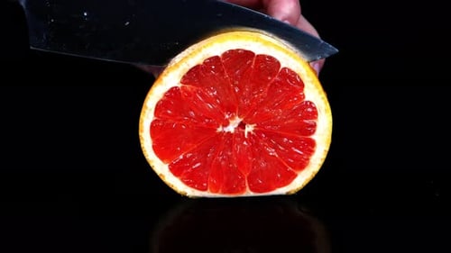 Fresh Grapefruit Sliced with Knife on Black Background