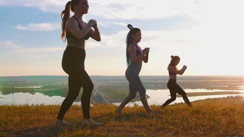 Women Exercising on Hill at Sunset