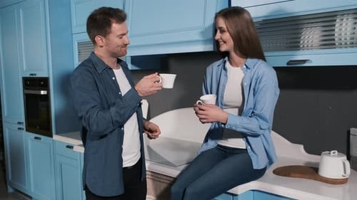 Man Offers Coffee to Woman in Kitchen