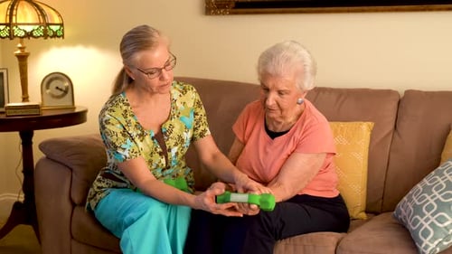 Woman Guides Senior Woman in Dumbbell Exercise