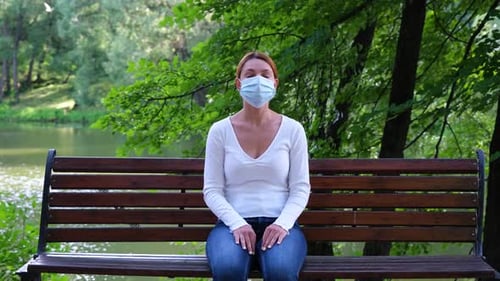Pandemic, Coronavirus Quarantine. Young Woman Sits on a Park Bench Alone During an Epidemic