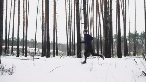 Young Adult Running in Snowy Winter Forest