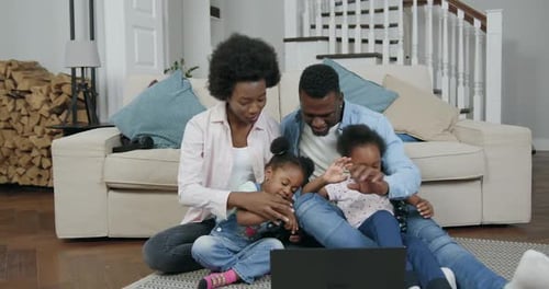 Familia de piel negra con niños pequeños que juegan juntos videojuegos en una computadora portátil