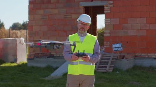 Professional Builder Drone Operator Checks the Work Controls an Aircraft Holding Remote Controller