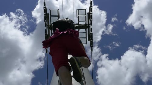 Man Ascends Tower Ladder in Blue Sky