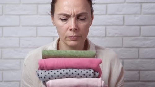 Woman Holding a Stack of Folded Clothes