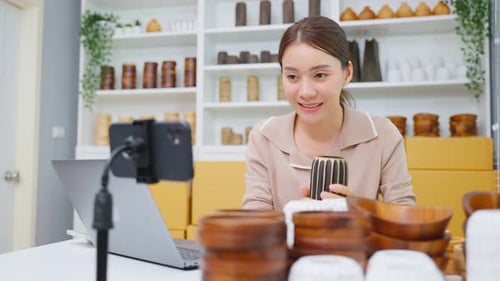Asian young woman sell vase product online live streaming at home. Remote buying shopping concept.