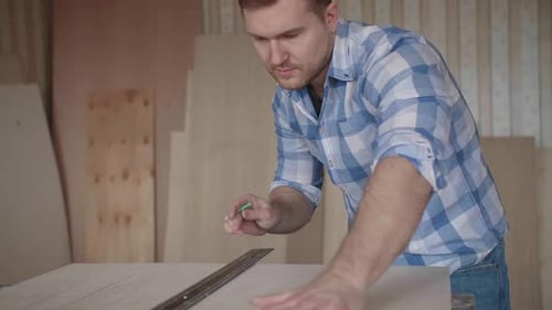 Man Measures Wood With Ruler and Pencil