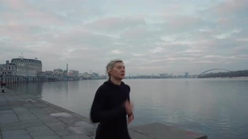 Sportswoman Running Near River in Evening