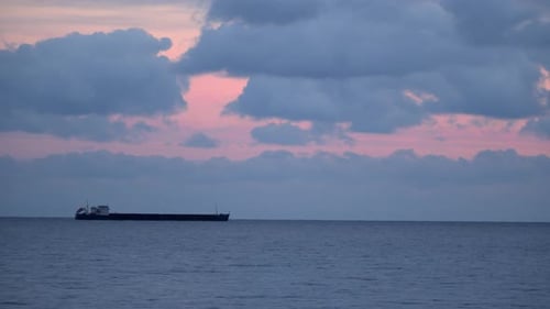Cargo Ship Sailing on the Ocean at Sunset