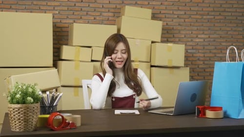 Young Woman Working at Desk with Boxes and Laptop