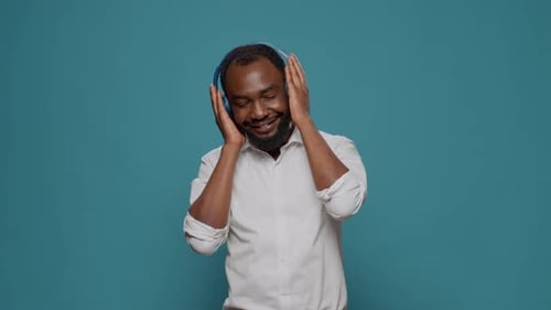 Man Smiling and Listening to Music on Headphones