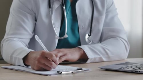 Physician Writing on Clipboard in Office Setting