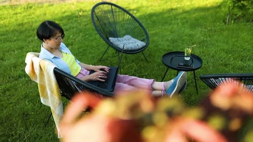 Freiberufliche Frau arbeitet zu Hause im Hinterhof am Laptop