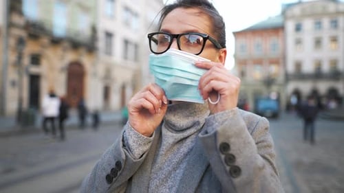 Woman Puts On Face Mask in City Square