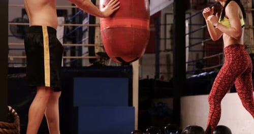 Woman Boxing While Man Holds Punching Bag