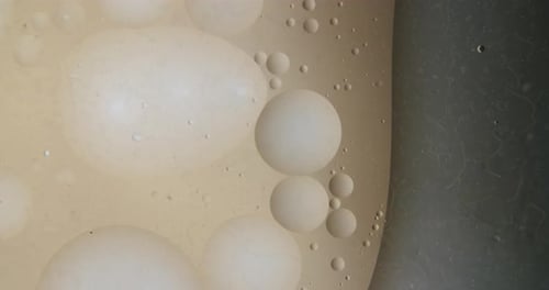 Extreme macro shot of small bubblesing in a viscous transparent liquid. Dark background.