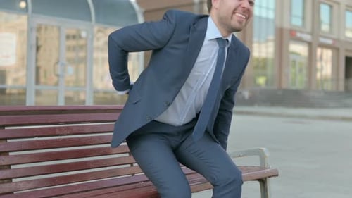 Man in Suit Experiencing Back Pain on Bench