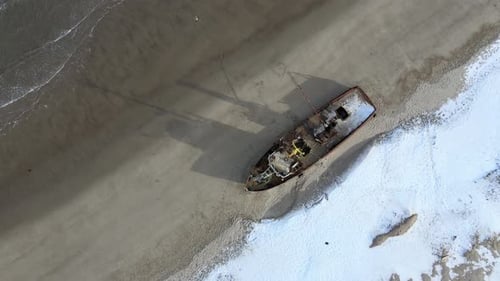 Luftaufnahme alter zerstörter Fischerschiffe, die in der verschneiten Wintersaison an der Küste ertrunken sind