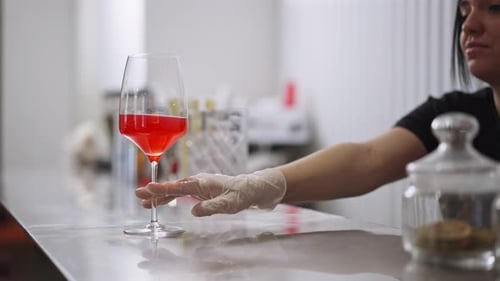 Bartender Serves Red Cocktail in Wine Glass