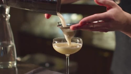 Bartender Pours Alcohol in Glass Through a Sieve at the Bar