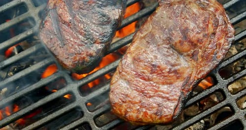Sizzling Steaks on Grill Over an Open Fire