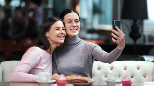 Smiling Women Taking Selfie at Restaurant Together