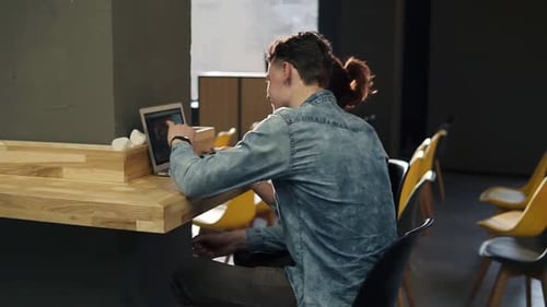Couple of Two Young People Sitting in an Empty Indoors Area of Coworking Space Looking at Photos on