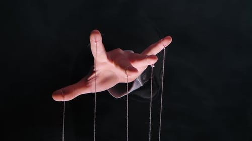 Hand des Diktators im Business-Anzug mit Schnüren an den Finger zur Steuerung der Puppe