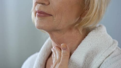 Mature Woman Massaging Her Neck in a Close-Up