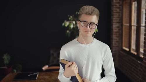 Young Adult Smiling Holding a Book Indoors