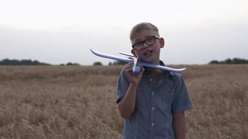 Happy guy with a toy airplane on a wheat field in the sunset light.