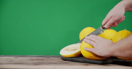Les mains des hommes coupent le melon en deux moitiés.