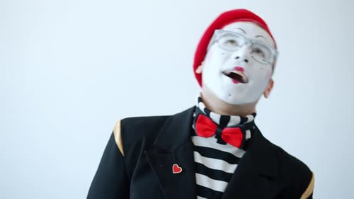 Shy Mime Artist in bunten Kleidern und Brillen lacht Mund mit Hand bedeckt