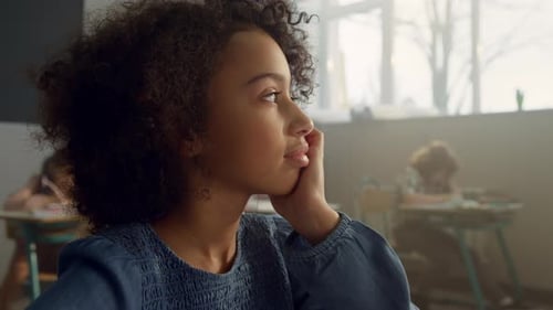 Bored Kid Sitting at Desk in Classroom
