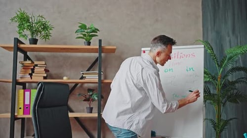 Male Teacher Writing Grammar Lesson on Whiteboard
