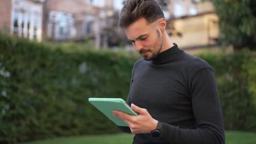 Young Adult Using Tablet Device in Urban Green Space