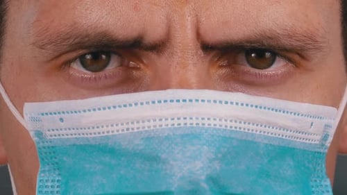 Young Man in a Medical Protective Face Mask Looking at the Camera on the Street Background