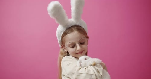 Happy Girl Hugs White Rabbit in Studio